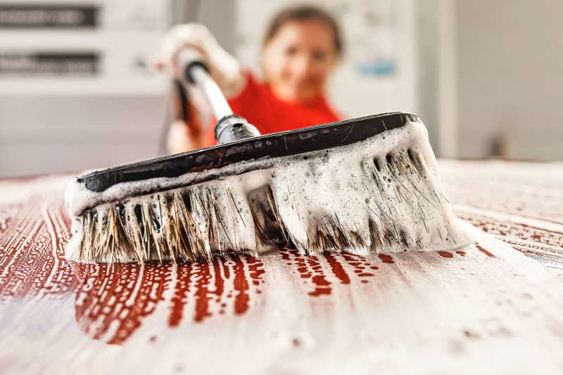 VGbrandstoffen_0008_Closeup-detail-on-white-soap-foam-and-brush-with-suds-moving-over-roof-as-young-woman-cleans-her-car